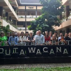 De bezoekers van de IRTI conferentie poseren voor het logo van de gastuniversiteit, Duta Wacana Christian University.